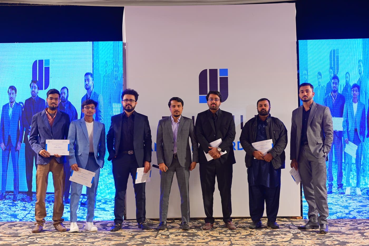 Colleagues holding their certificates on stage at the Tribuild Annual Awards